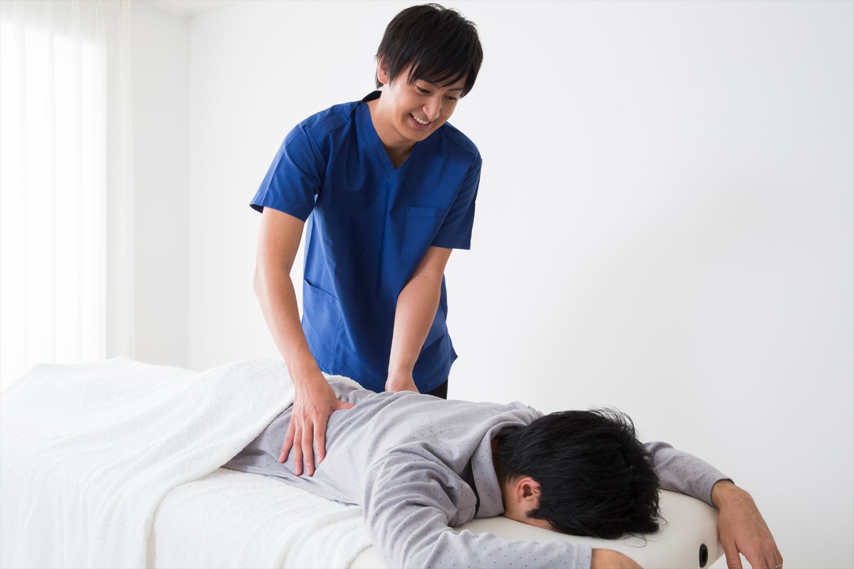 男性の腰を施術するスタッフ